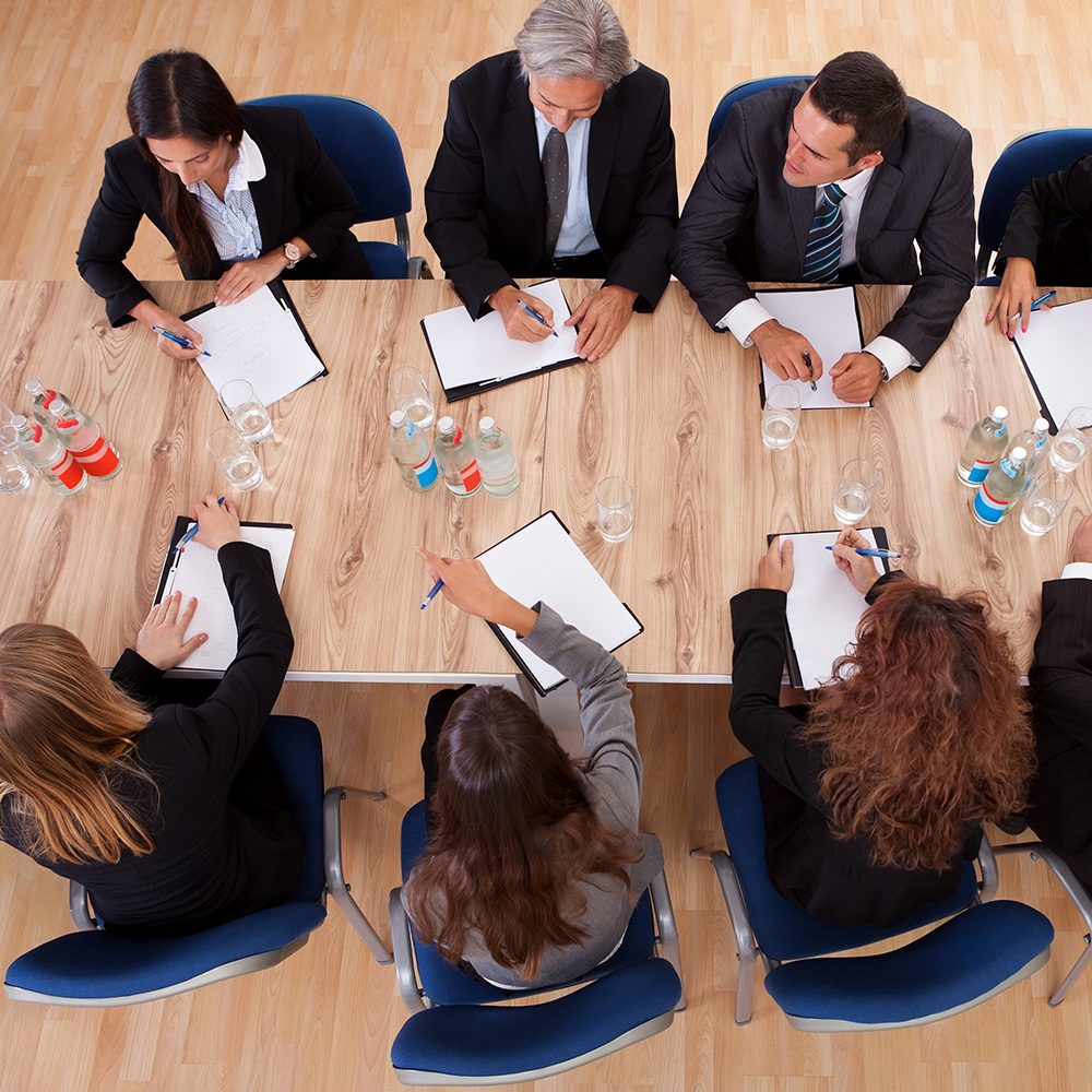 A group of people sitting at a table with papers.