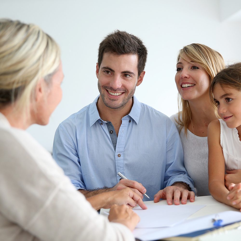 Family signing paperwork with an agent.