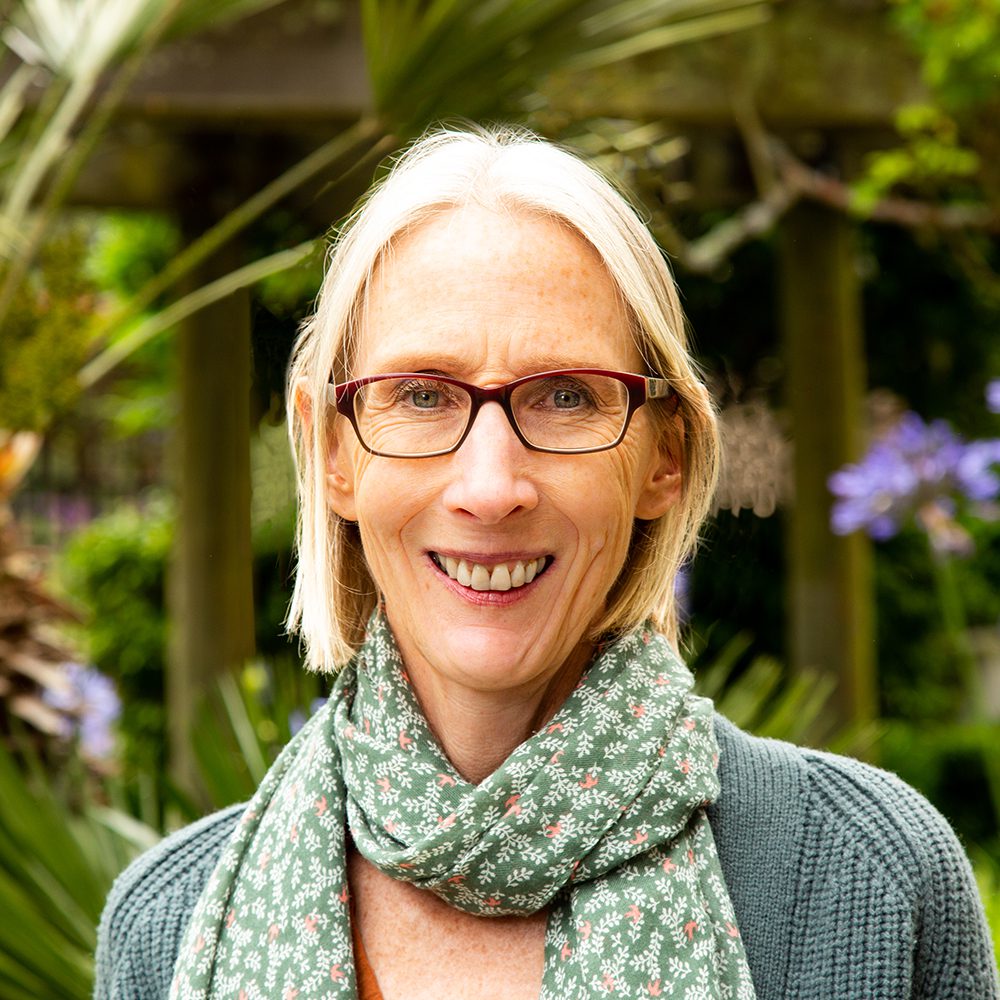 Smiling woman wearing glasses and scarf.