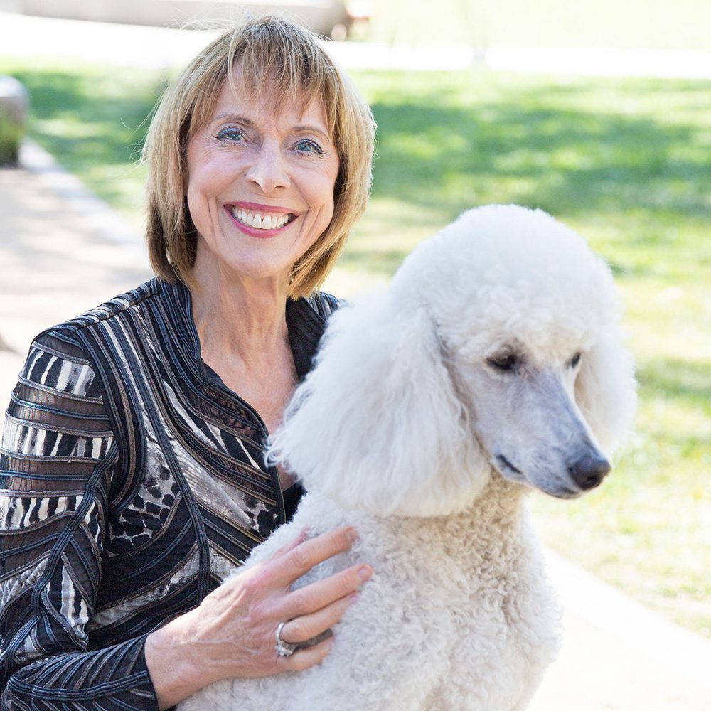 Woman smiling with white poodle.